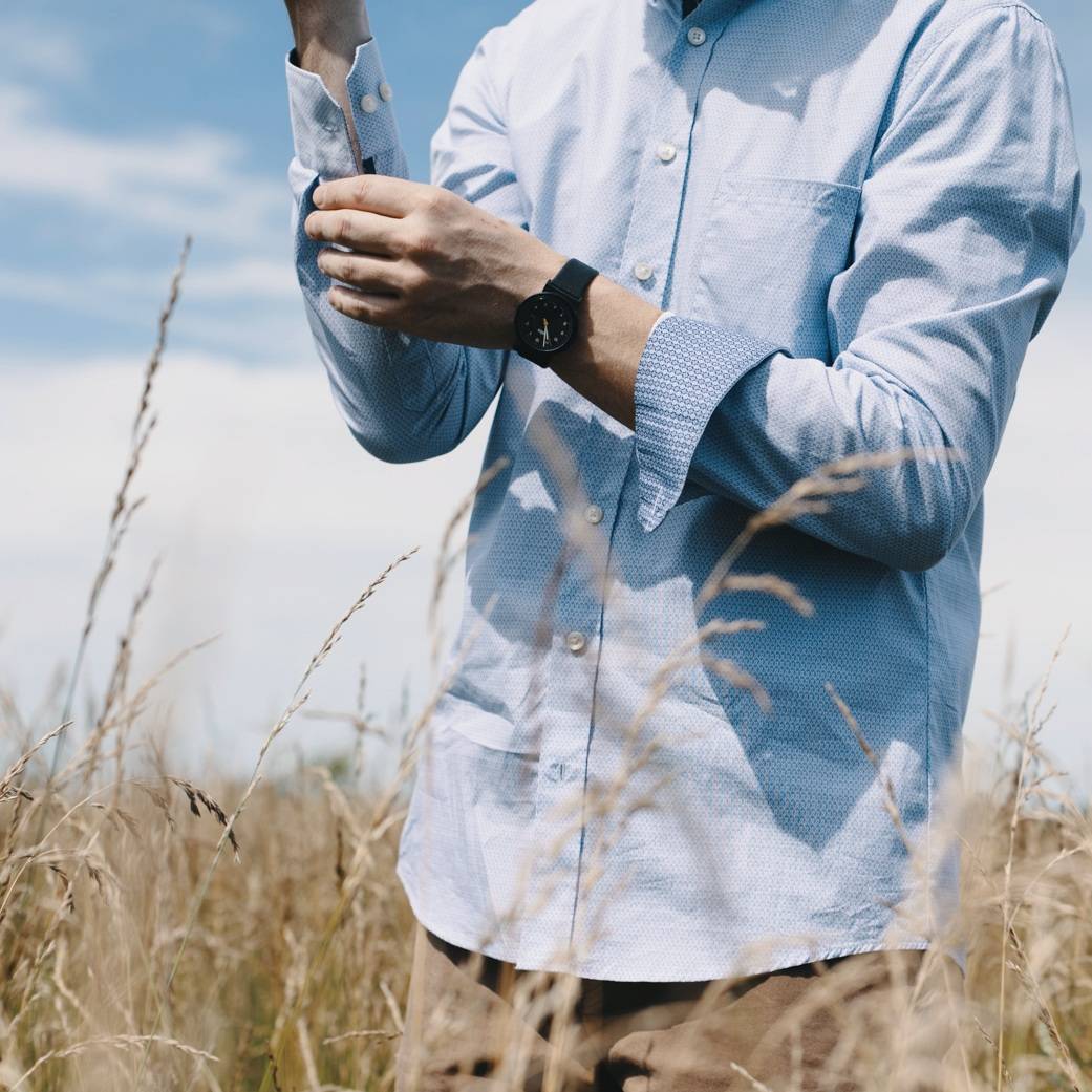 close up of man standing in wheat field wearing dress shirt and khakis